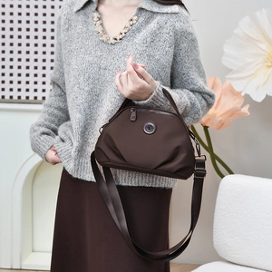 Detail of dark brown crossbody bag on model with adjustable strap and metal logo