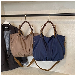 Detail of cargo canvas tote with leather handles and rivets in khaki and navy