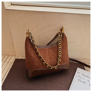 Close-up of retro brown shoulder bag with matte suede texture and gold chain detail