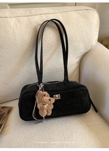 Detalle de bolso de hombro de ante negro con cierre giratorio plateado y colgante de osito