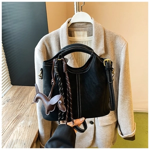Detail of black leather handbag with white stitching and a brown dog charm accessory