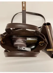 Vue détaillée de l'intérieur spacieux du sac seau marron foncé avec ses articles quotidiens