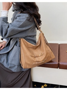 Détail du sac cabas en cuir fauve avec coutures blanches et boucles en décor automnal