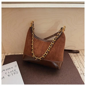 Detail of a brown shoulder bag with mixed matte suede and glossy leather textures