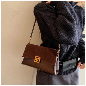 Detail of retro mixed-media shoulder bag with suede texture and gold metal buckle