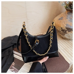 Detail of hobo bag featuring matte suede and smooth leather with gold chain accents