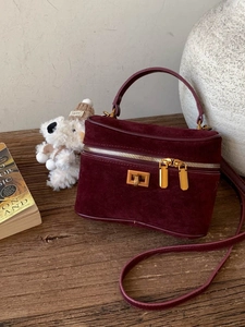 Sac boîte en daim bordeaux avec finitions dorées et poignée pour un porté élégant