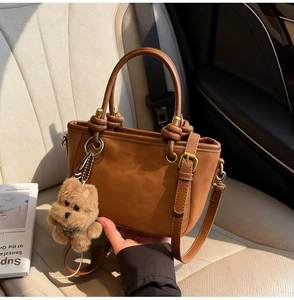 Détail d'un sac à main en daim marron avec boucle et breloque chien en peluche