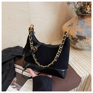 Detail of black suede and leather hobo bag with gold chain on a vintage wood background