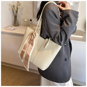 Nahaufnahme der beigen Tragetasche aus Lychee-Leder mit dekorativem Fashion-Print-Schal