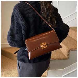 Detailed view of brown matte leather crossbody bag with iconic gold geometric G buckle