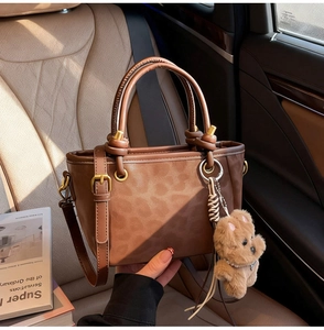Sac à main léopard marron avec poignée nouée et breloque ours sur siège de voiture