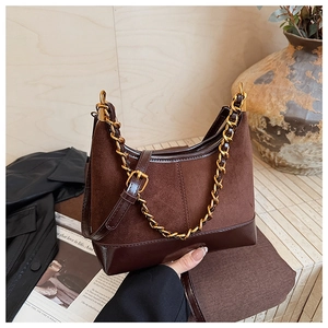 Close-up of the vintage brown matte suede texture and chunky gold chain strap on the handbag