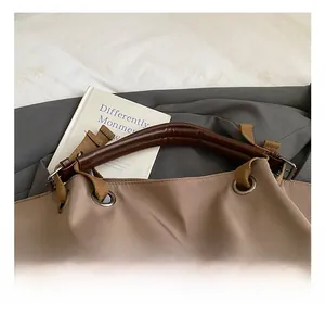 Detail shot of a large tote bag featuring reinforced brown leather handles and metal hardware