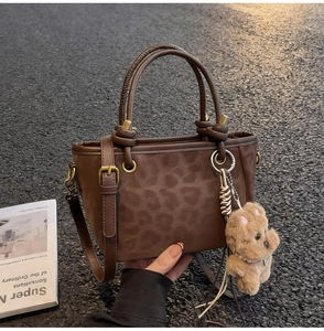 Détail de la texture léopard gaufrée sur sac rétro marron avec charm chien en peluche