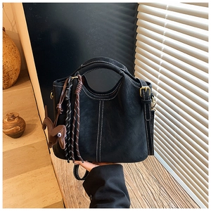 Detail of black vintage matte leather tote bag with contrast stitching and puppy charm