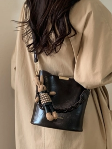 Vintage dark brown leather bucket bag with a cute knit bunny charm and woven strap