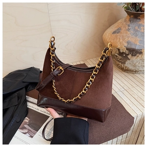 Detail of dark brown suede and leather crossbody bag with chunky gold chain strap