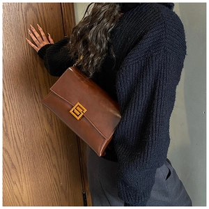 Detail of vintage brown shoulder bag with polished gold buckle and glossy leather
