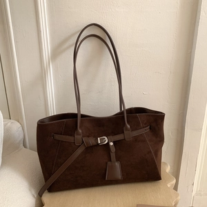 Detailed shot of dark brown matte suede tote bag with leather strap buckle on display