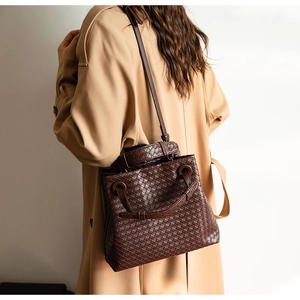 Detail of a dark brown woven leather tote with wide intrecciato pattern and adjustable strap