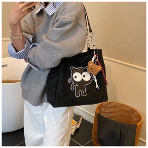 Détail du sac cabas en toile noire avec écusson chat de dessin animé et ours peluche