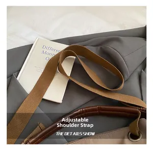 Detail view of adjustable fabric shoulder strap and brown leather handle on a canvas tote bag