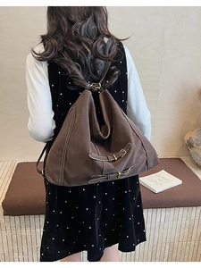 Vue détaillée du sac à dos vintage en daim marron avec coutures blanches et boucles