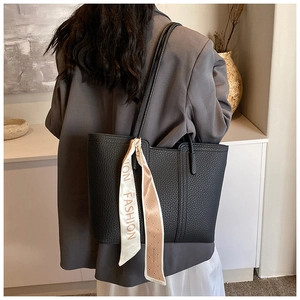 Detail einer schwarzen Leder-Tote-Bag mit modischem Seidentuch am Griff für Damen