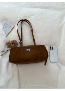 Detalle de bolso de ante marrón con cierre de plata y un colgante de oso de peluche
