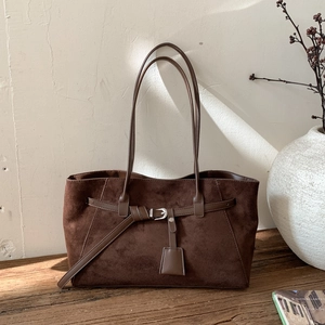 Retro brown suede tote bag with leather strap detail on a rustic wooden table