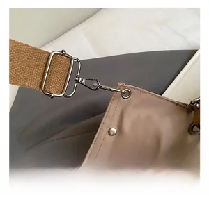Detailed macro view of the metal hook, buckle and webbing strap on the khaki tote bag