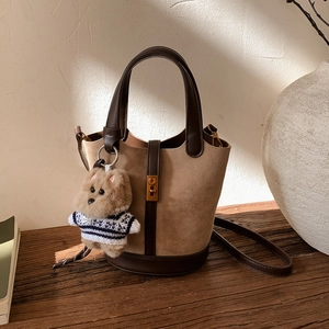Détail du sac seau marron avec charme de chien en peluche et serrure dorée