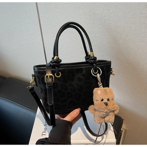Detail der schwarzen Tote-Tasche mit Leopardenprägung, Goldbeschlägen und Teddy-Anhänger