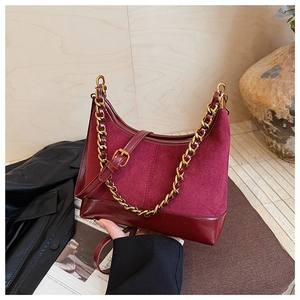 Close-up of matte burgundy shoulder bag with thick gold chain and mixed leather texture