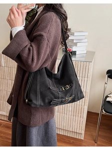 Détail du sac hobo avec coutures contrastées blanches et boucles dorées décoratives