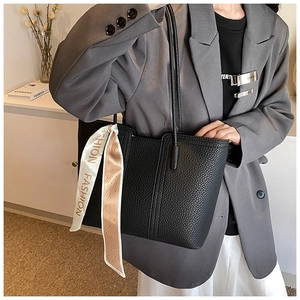 Detail der schwarzen Tote Bag mit Litschimuster und dekorativem Seidenband am Tragegriff