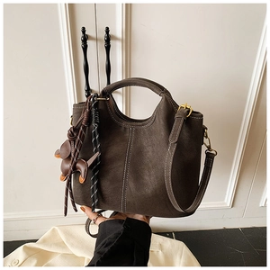 Detail of dark brown bucket bag with contrast white stitching and puppy charm