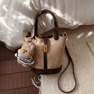 Détail du sac seau en daim avec garniture en cuir, fermoir en métal et ourson