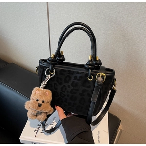 Détail du sac seau noir à motif léopard avec un petit pendentif ours en peluche marron