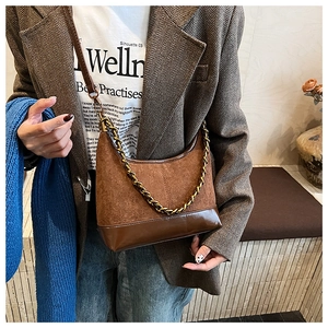 Detail view of brown suede and leather shoulder bag with golden chain and sleek leather strap