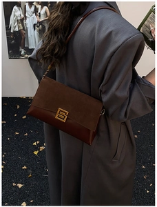 Detailed view of a dark brown retro crossbody bag with suede stitching and gold buckle