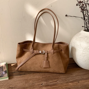 Detail of vintage matte caramel tote bag with decorative buckle strap and slim handles