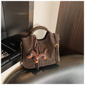 Detail of vintage brown suede bucket bag with long strap and dachshund dog charm
