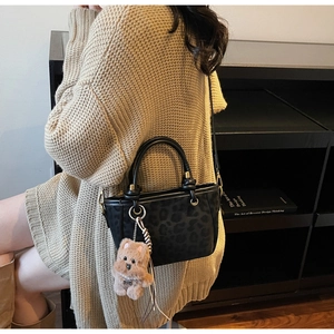 Détail du sac cabas léopard noir avec breloque ours et poignées rondes robustes