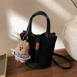 Détail du sac seau noir en daim avec boucle métallique et breloque ours en peluche