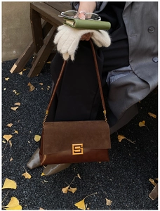 Detail of vintage dark brown shoulder bag with gold buckle on a retro autumn background