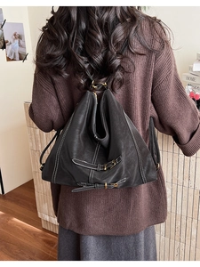 Détail d'un sac à dos en cuir noir avec surpiqûres blanches et boucles dorées élégantes