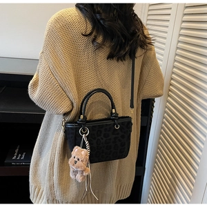 Détail du sac à bandoulière noir à motif léopard avec un pendentif chien en peluche