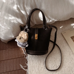Détail du sac seau noir en cuir avec fermoir doré et pendentif peluche chien mignon